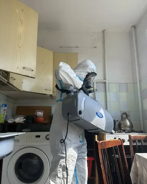 Мастер выполняет дезинсекцию кухни